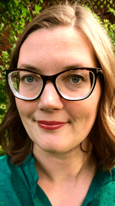 Headshot of Nell Haynes. She has brown shoulder length straight hair, and is wearing glasses and a green shirt.